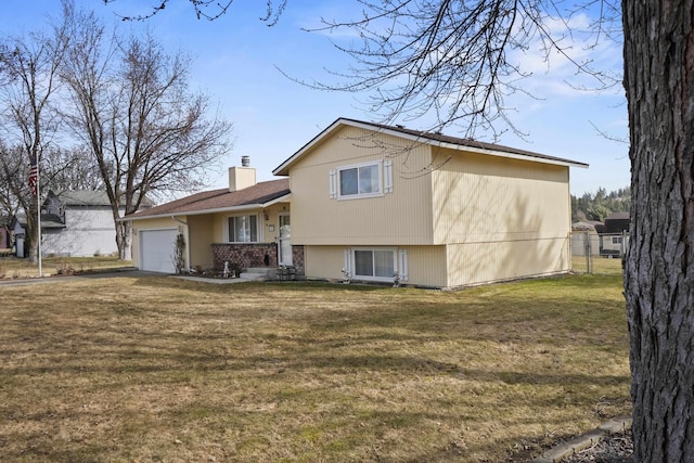 back of house featuring an attached garage, a chimney, fence, and a yard