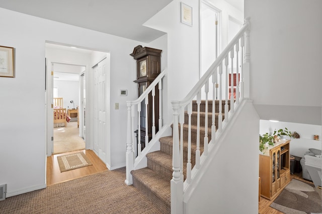 stairway featuring baseboards, visible vents, and carpet flooring