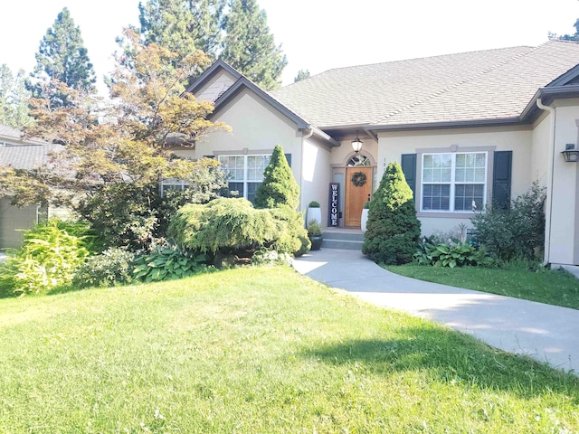 ranch-style home featuring stucco siding, a front lawn, and roof with shingles