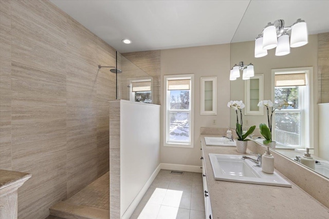 bathroom with tile patterned flooring, visible vents, baseboards, double vanity, and walk in shower