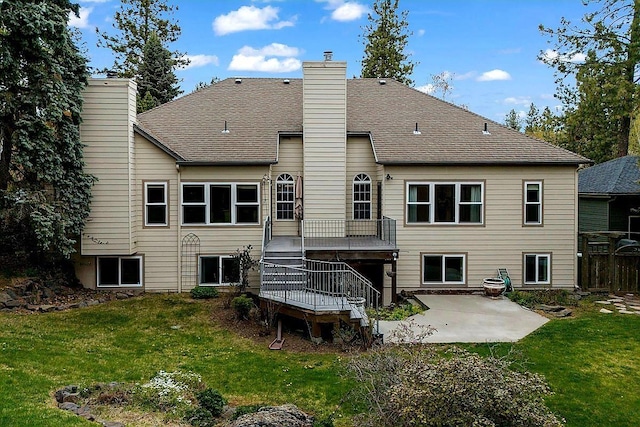 rear view of property with a patio area, a lawn, a chimney, and a wooden deck