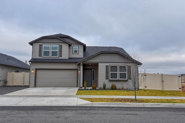 view of front of property with concrete driveway, an attached garage, fence, and a gate