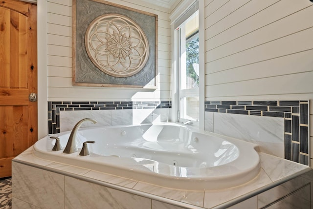 bathroom featuring a jetted tub and wooden walls