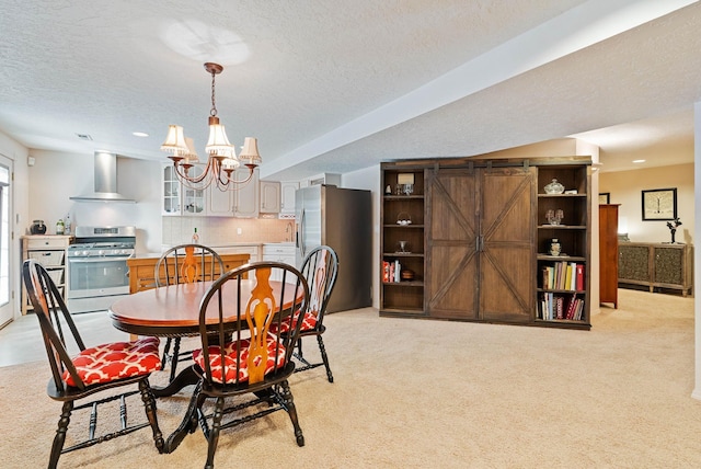 dining room with an inviting chandelier, a barn door, a textured ceiling, and light colored carpet