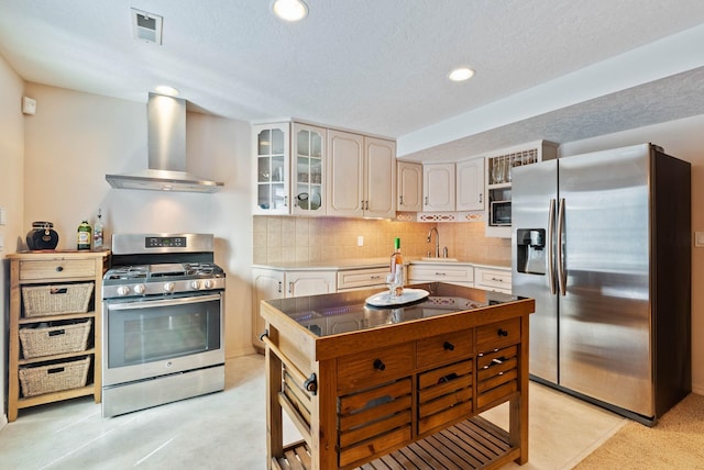 kitchen featuring visible vents, decorative backsplash, wall chimney exhaust hood, appliances with stainless steel finishes, and a sink