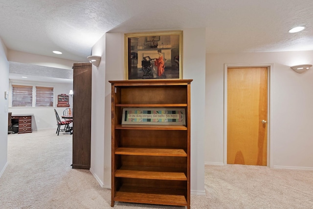 hallway with carpet floors, baseboards, and a textured ceiling