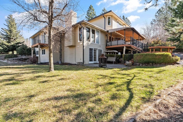 back of property with a lawn, a patio, a chimney, stairs, and a deck