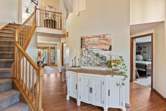 interior space featuring dark wood-style floors, a towering ceiling, and stairs