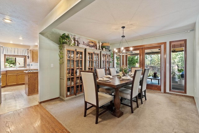 dining room featuring a textured ceiling, light wood-style flooring, recessed lighting, a notable chandelier, and baseboards