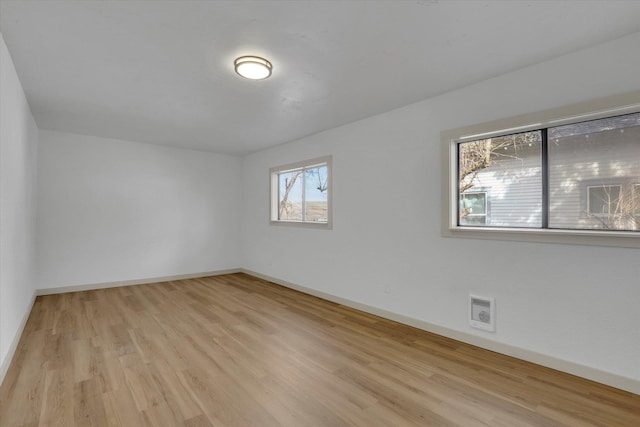 empty room featuring visible vents, baseboards, and wood finished floors