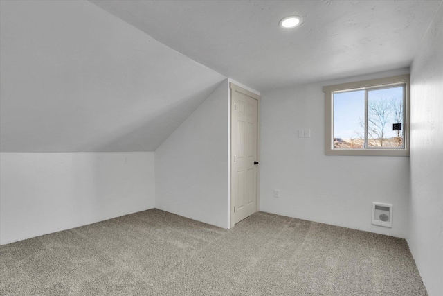 additional living space featuring vaulted ceiling and carpet flooring