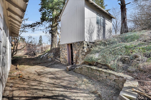 view of side of property with stone siding and a patio area