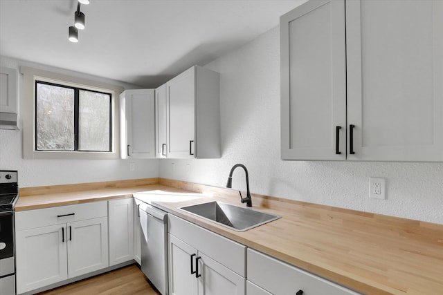 kitchen featuring a textured wall, appliances with stainless steel finishes, a sink, and butcher block counters