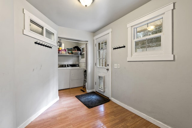 entryway featuring baseboards, light wood finished floors, and separate washer and dryer