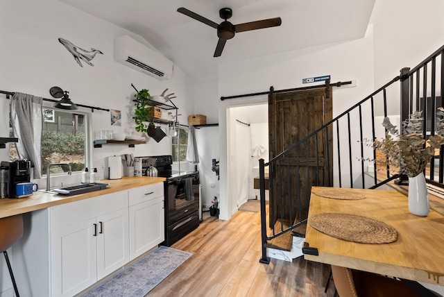 kitchen featuring a barn door, a wall unit AC, black electric range oven, open shelves, and a sink