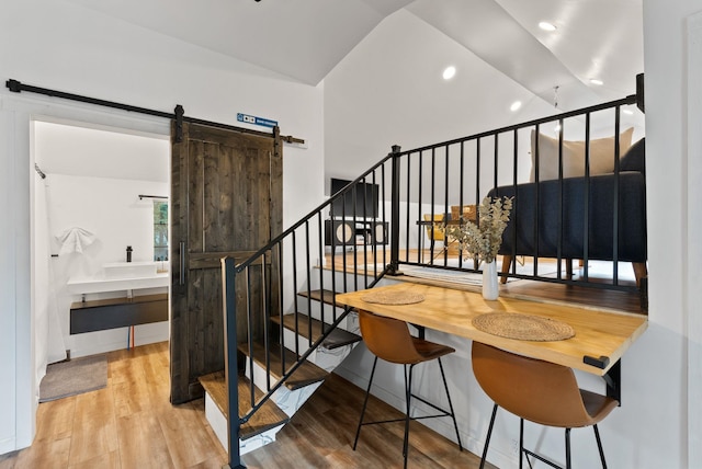 stairs with recessed lighting, wood finished floors, and a barn door