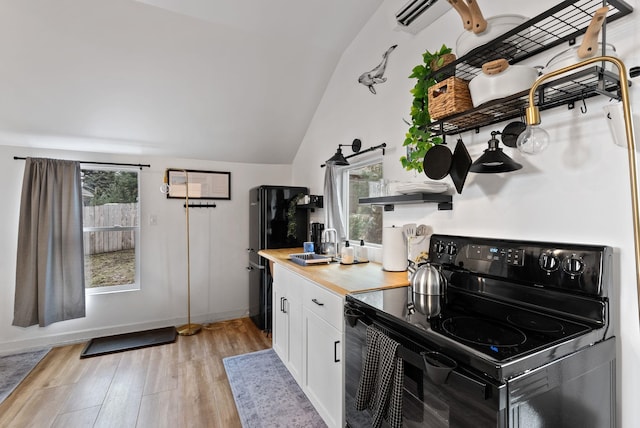 kitchen featuring lofted ceiling, black range with electric cooktop, light wood-style flooring, a sink, and open shelves