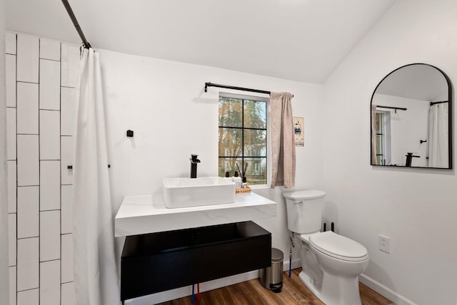 bathroom with curtained shower, toilet, vaulted ceiling, wood finished floors, and baseboards