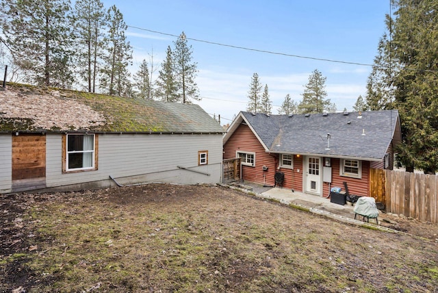 rear view of house featuring roof with shingles, fence, and a patio