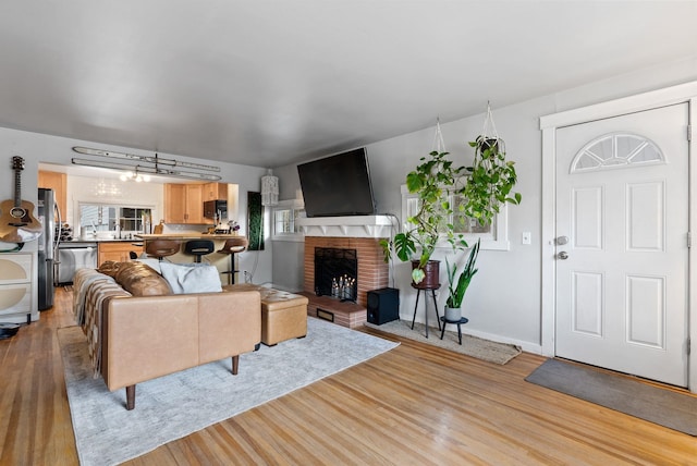 living room featuring a fireplace, light wood-style flooring, and baseboards