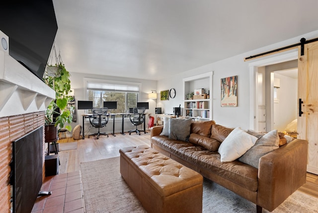 living area featuring a barn door, a fireplace, and wood finished floors