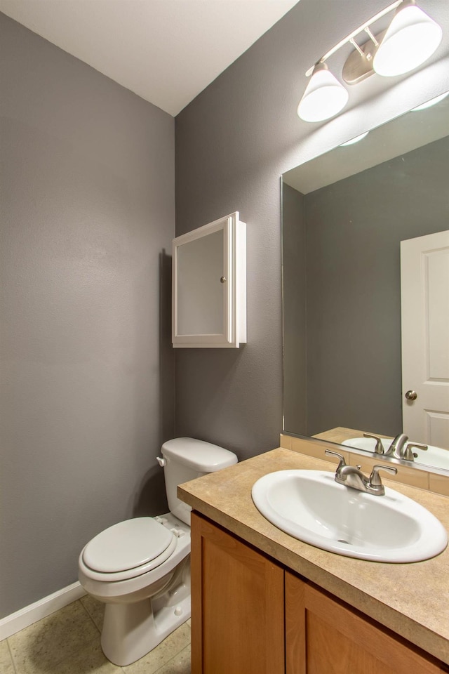 bathroom with toilet, tile patterned floors, baseboards, and vanity