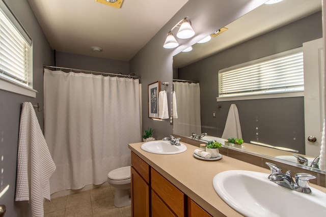 full bath with toilet, double vanity, a sink, and tile patterned floors