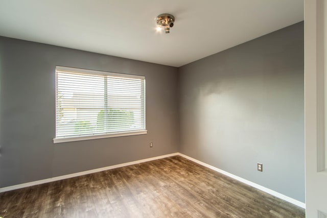 unfurnished room with dark wood-type flooring and baseboards