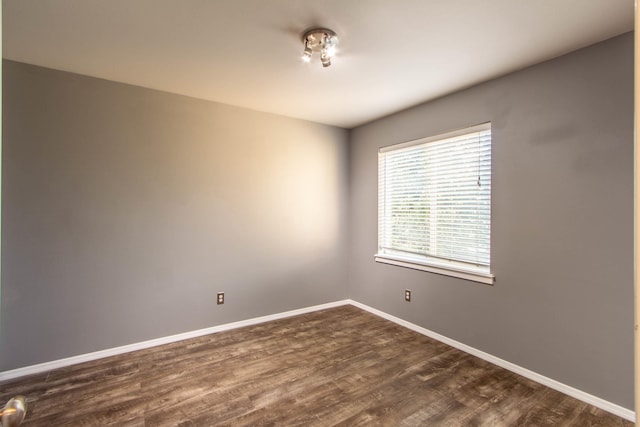 spare room featuring dark wood-style floors and baseboards