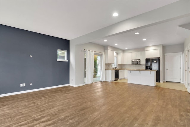 unfurnished living room featuring light wood-style floors, baseboards, and recessed lighting