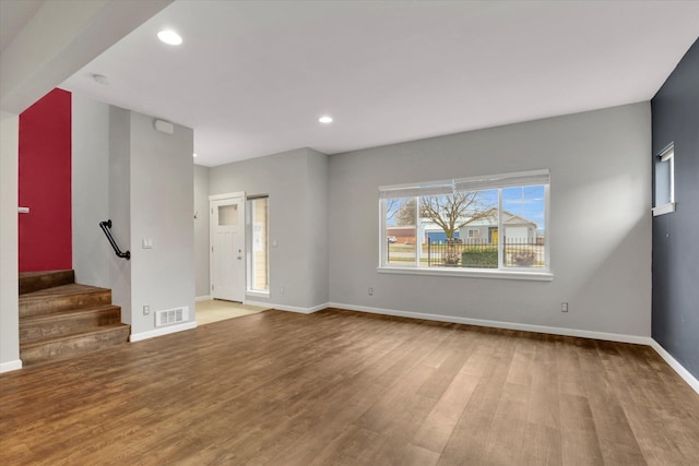 unfurnished living room featuring recessed lighting, wood finished floors, visible vents, baseboards, and stairs