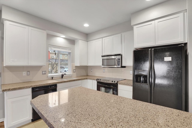 kitchen with recessed lighting, white cabinets, a sink, light stone countertops, and black appliances