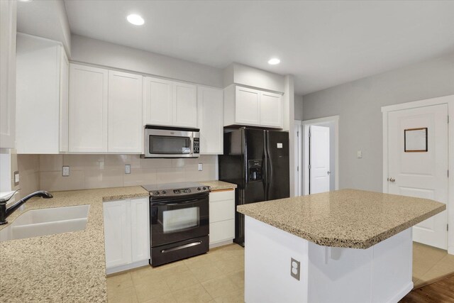 kitchen featuring a kitchen island, a sink, white cabinets, black appliances, and tasteful backsplash