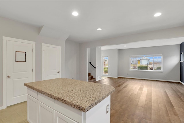 kitchen with a center island, white cabinetry, light stone countertops, and recessed lighting