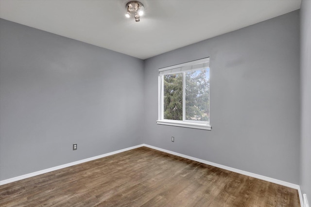 spare room with dark wood-style floors and baseboards