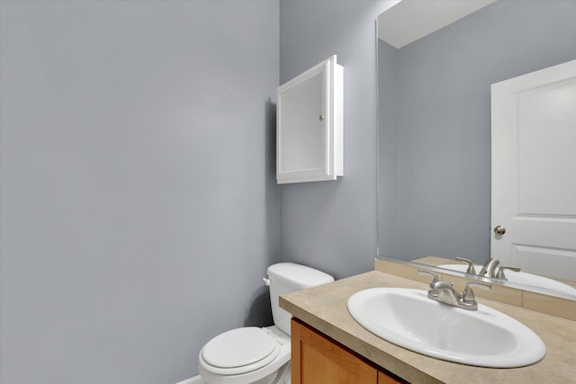 half bath with baseboards, vanity, and toilet