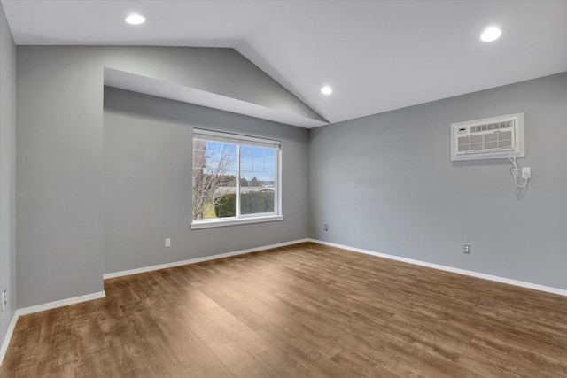 unfurnished room featuring lofted ceiling, recessed lighting, wood finished floors, baseboards, and an AC wall unit