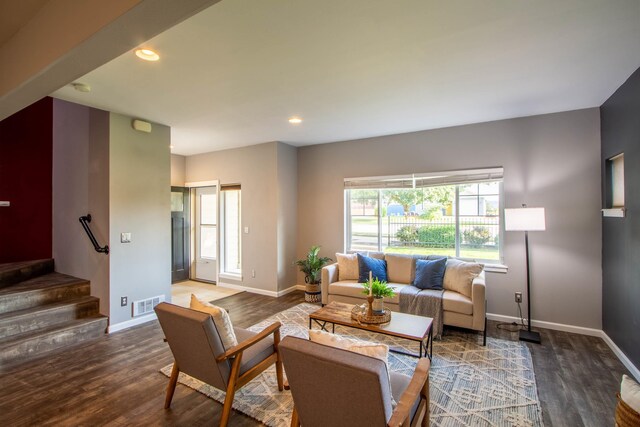 living room with wood finished floors, visible vents, baseboards, and stairs