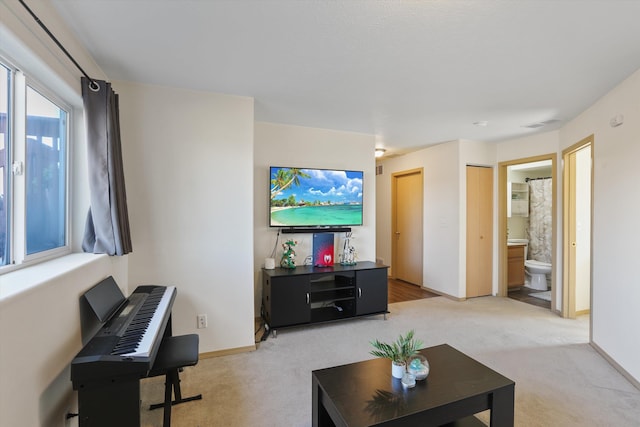 living area with baseboards, visible vents, and light colored carpet