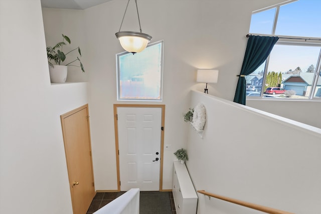 entryway featuring dark tile patterned floors and a high ceiling