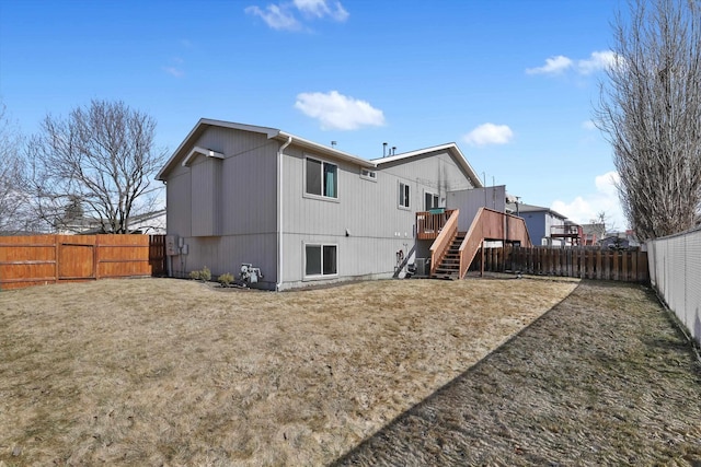 back of property featuring a fenced backyard, stairway, a lawn, and a wooden deck