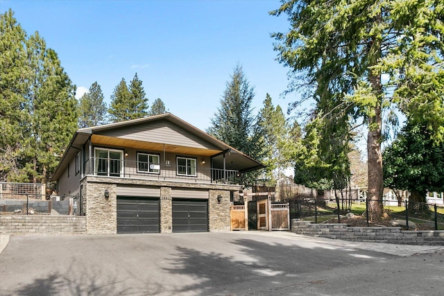 view of front of house featuring fence, stone siding, and driveway