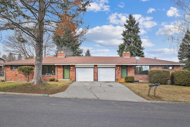 ranch-style home with brick siding, a chimney, concrete driveway, an attached garage, and a front lawn