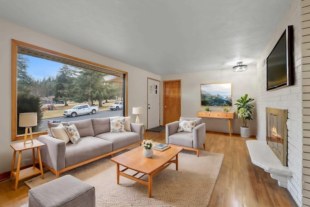 living area featuring a brick fireplace and light wood-style flooring