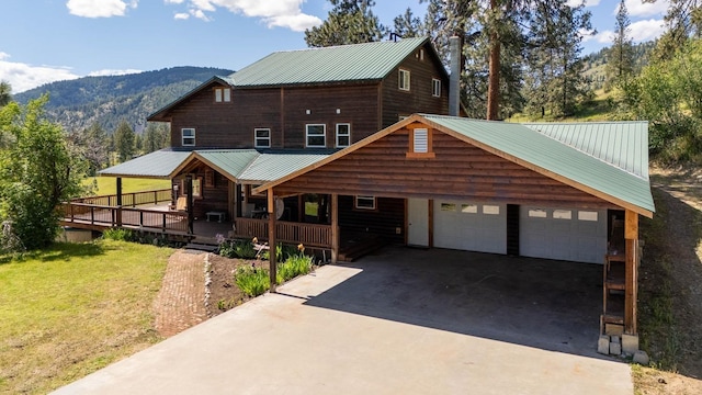 view of front of property featuring covered porch, a mountain view, concrete driveway, and a front yard