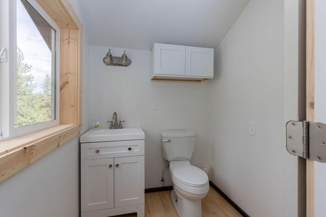 bathroom with baseboards, vanity, toilet, and wood finished floors