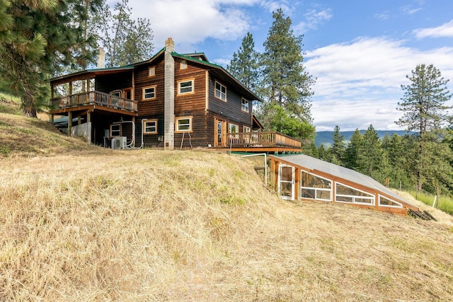 back of property with a deck, a chimney, and an outdoor structure