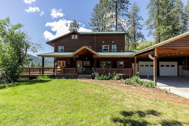 view of front of home with a porch, a front yard, metal roof, a garage, and driveway