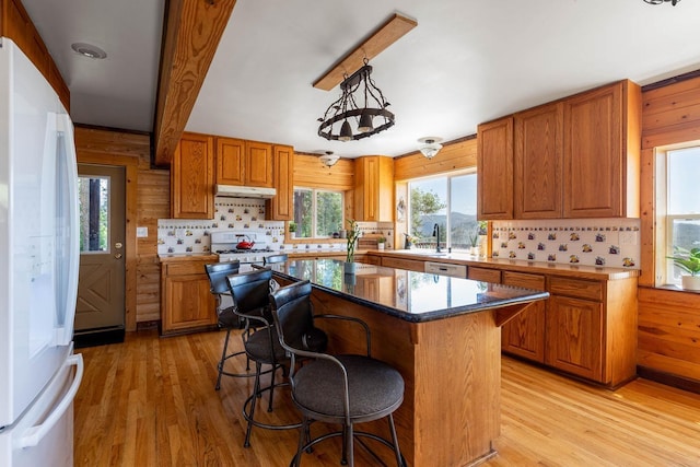 kitchen featuring brown cabinetry, white appliances, and under cabinet range hood