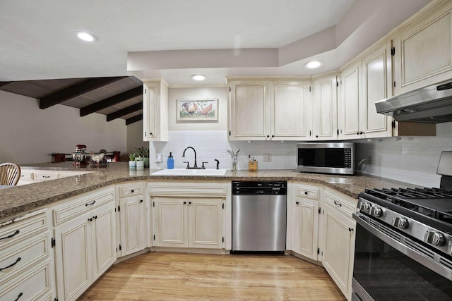 kitchen with decorative backsplash, appliances with stainless steel finishes, a sink, light wood-type flooring, and under cabinet range hood